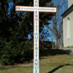 Neu errichtetes Holzkreuz an der Kirche St. Andreas mit dem Ostergruß "Der HERR ist auferstanden, er ist wahrhaftig auferstanden."